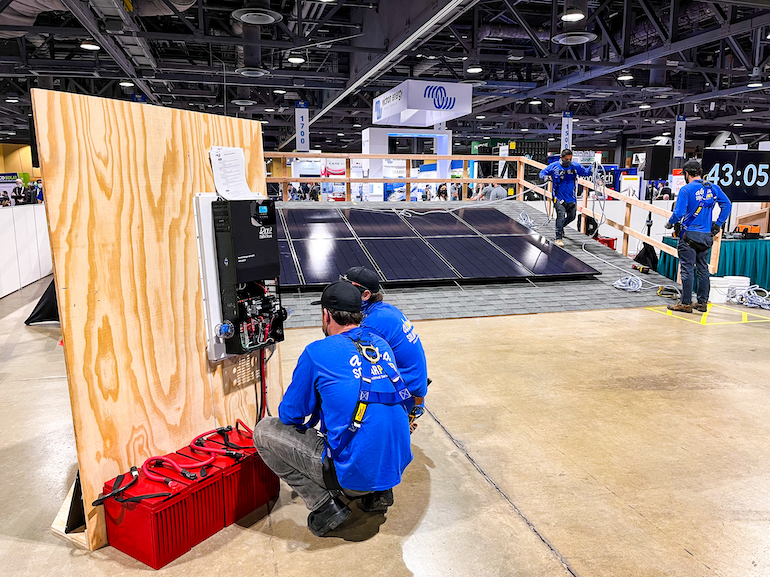 Installers connect a MidNite Solar hybrid inverter to a battery stack at the 2022 Solar Games.