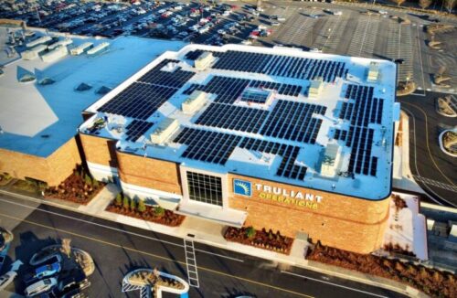 An overhead photo of a commercial building with a rooftop mostly covered in solar panels. 